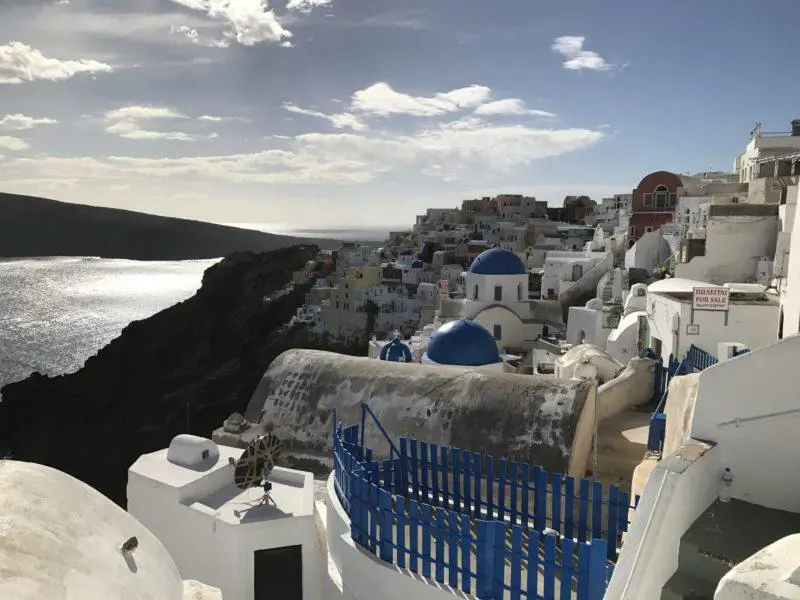 Este podría ser el mejor destino en Grecia, vista a través de los tejados de Santorini con paredes blancas y cúpulas azules que resaltan contra el resto de los edificios