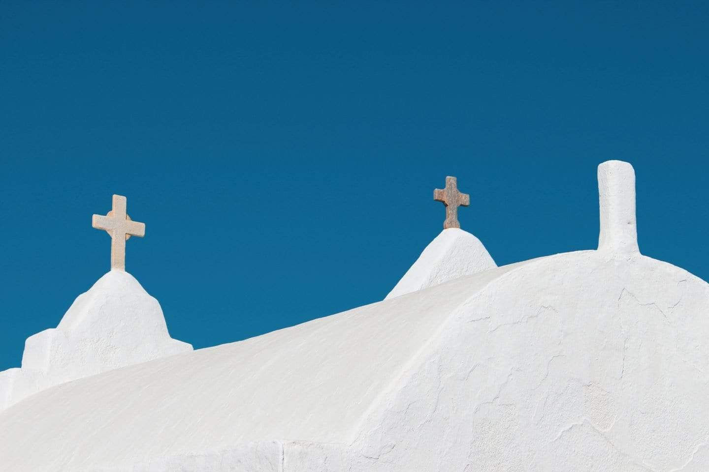Encuentre todas las mejores ciudades para visitar en Grecia, primer plano del techo blanco de una iglesia completa con cruces bajo un cielo azul claro