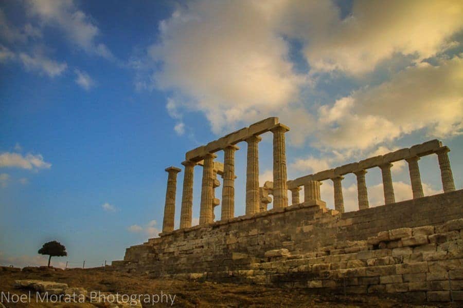 Encuentre sus lugares favoritos para ver en Grecia, una serie alta de ruinas de columnas ubicadas en la parte superior de una plataforma de piedra bajo un cielo azul con nubes