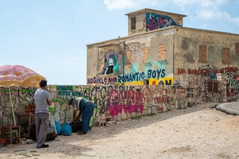 Consejos de guía de viaje de Albania, dos hombres parados frente a la pared y el edificio cubierto de graffiti colorido