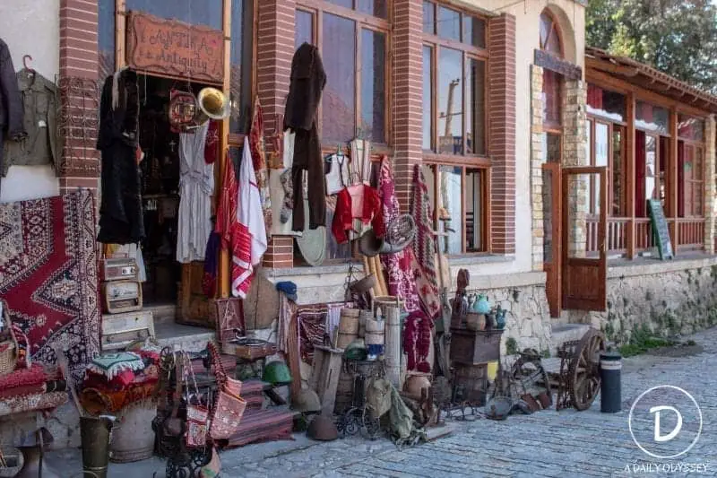 Encuentre sus cosas favoritas para comprar en Albania, frente al edificio con una colección de coloridas artesanías y artículos expuestos en la calle adoquinada con las puertas abiertas de manera tentadora