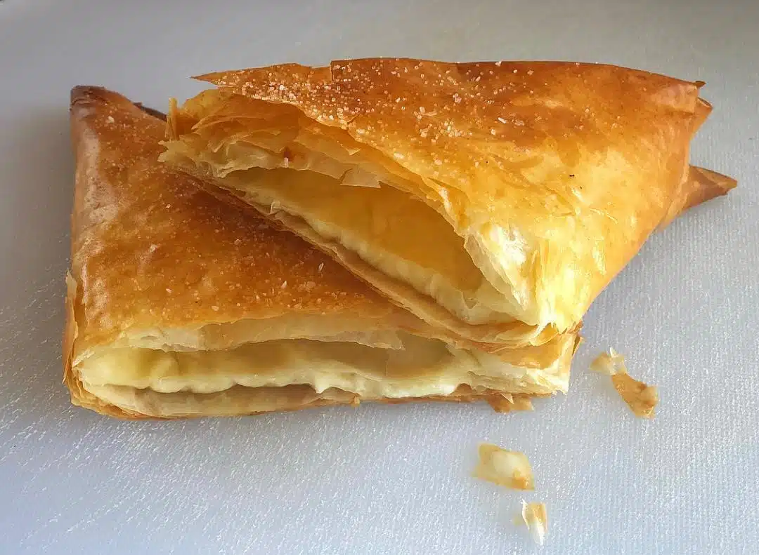 Platos griegos tradicionales para probar en Grecia, rebanadas de pastel de queso tiropita escamosas dispuestas una encima de la otra