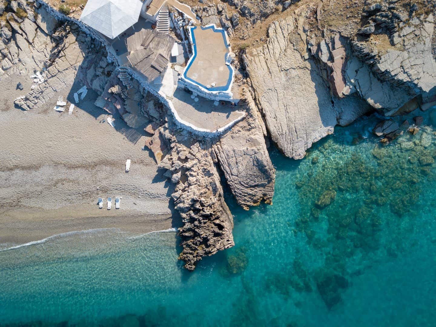 cómo pasar una semana en Albania, vista aérea de la estructura de piedra en un acantilado con vistas a la playa de arena y al océano azul transparente
