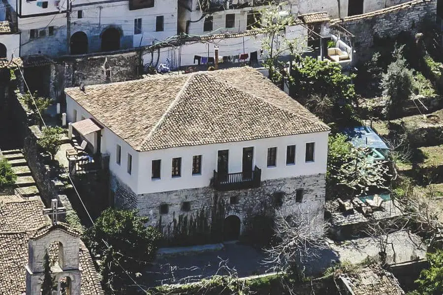 Backpacking Albania: The Best Hostels in Albania, foto aérea de un edificio cuadrado con paredes blancas y techo de tejas con balcón, rodeado de edificios