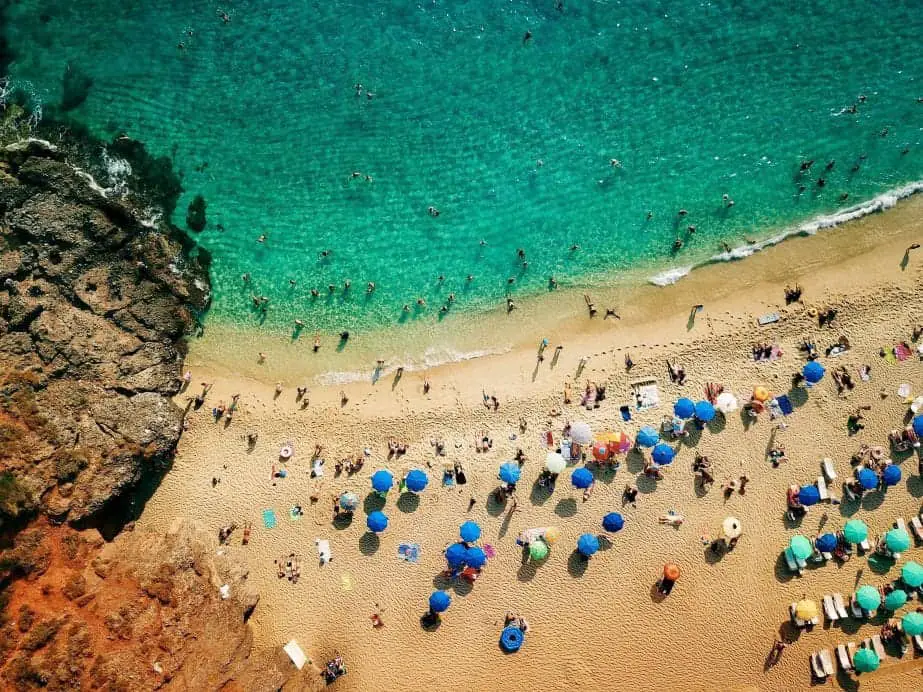 Relájese en la playa en los mejores destinos turísticos de Turquía, vista aérea de la playa con agua turquesa clara con gente nadando y tomando el sol junto a las sombrillas de playa