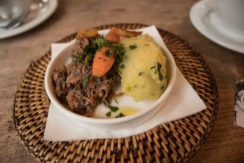 Las mejores escapadas baratas en Europa para amantes de la comida, plato de comida con carne mechada, zanahorias y puré de patatas.