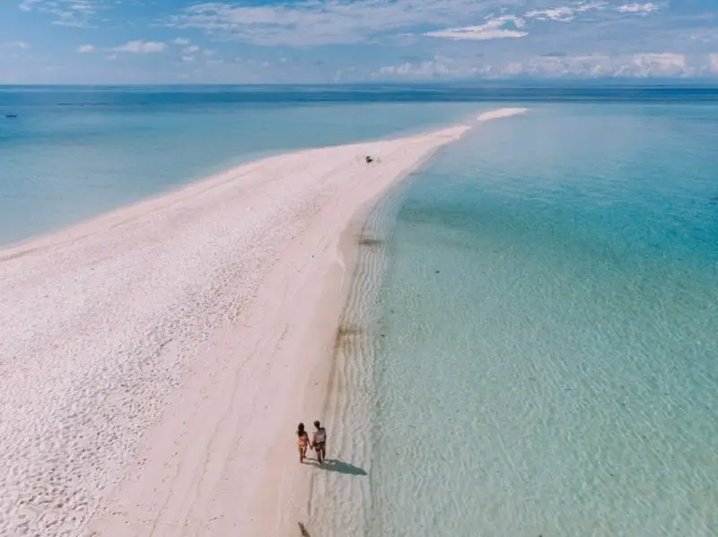 Isla popular en Filipinas, dos personas tomándose de la mano y caminando a lo largo de una península arenosa que se extiende hacia el mar
