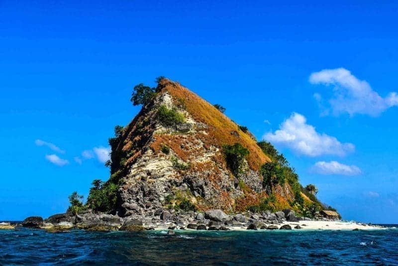 Islas de Filipinas, colina rocosa cubierta de musgo en una isla arenosa con una pequeña cabaña de madera a un lado
