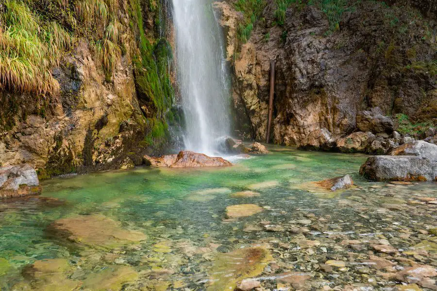 Caminata de Theth a Valbona: la mejor caminata en Albania, el fondo de una cascada que desemboca en agua transparente