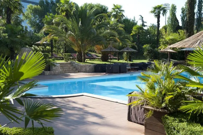 Los mejores hoteles de lujo en Albania, área de piscina exterior del hotel rodeada de tumbonas cubiertas y palmeras