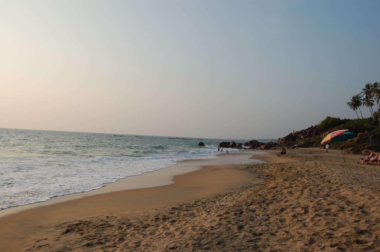 hermosas ciudades en Kerala, India, playa de arena al atardecer con algunas personas y sombrillas