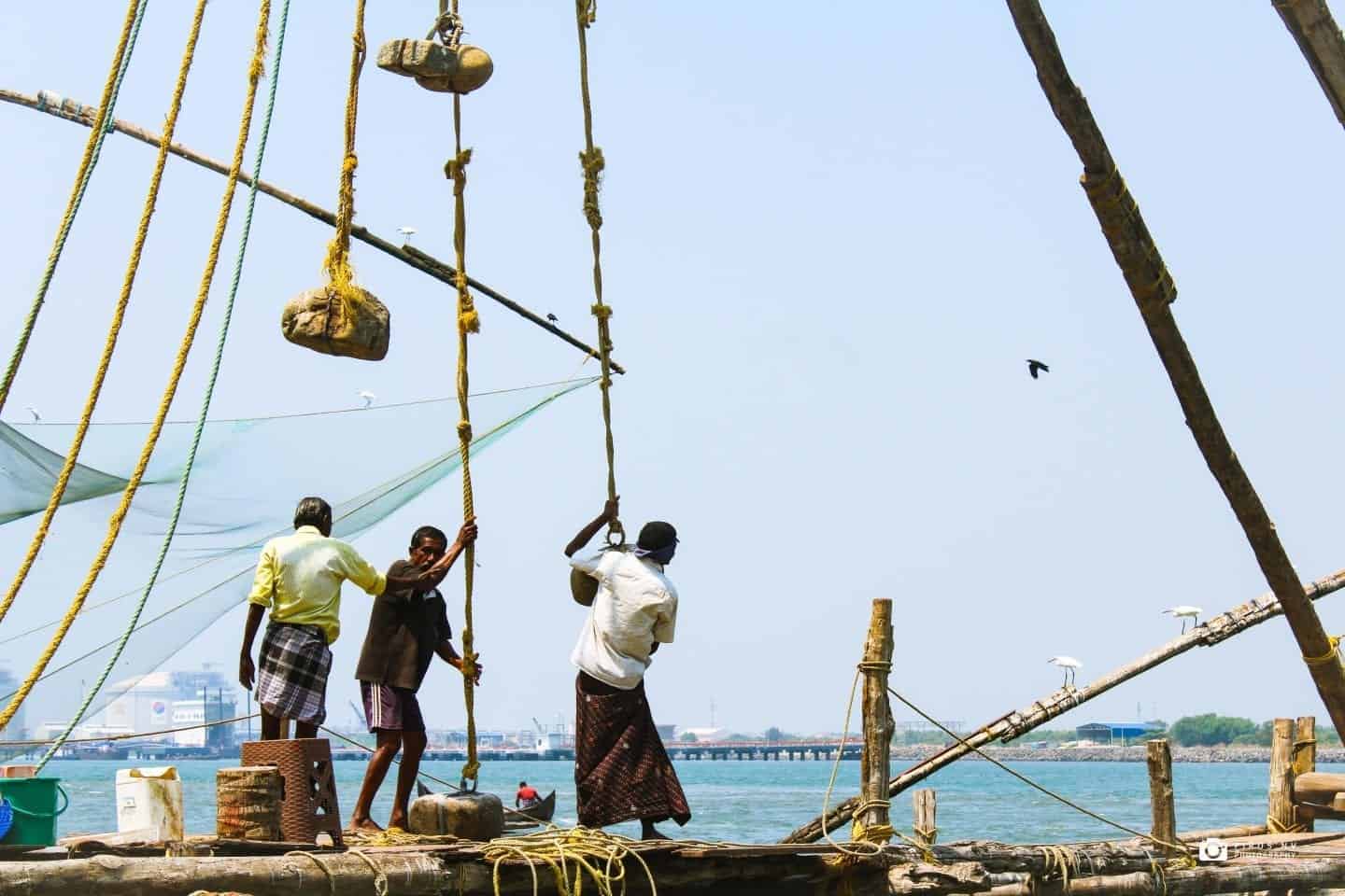lugares únicos para visitar en Kerala India, hombres en barco de pesca