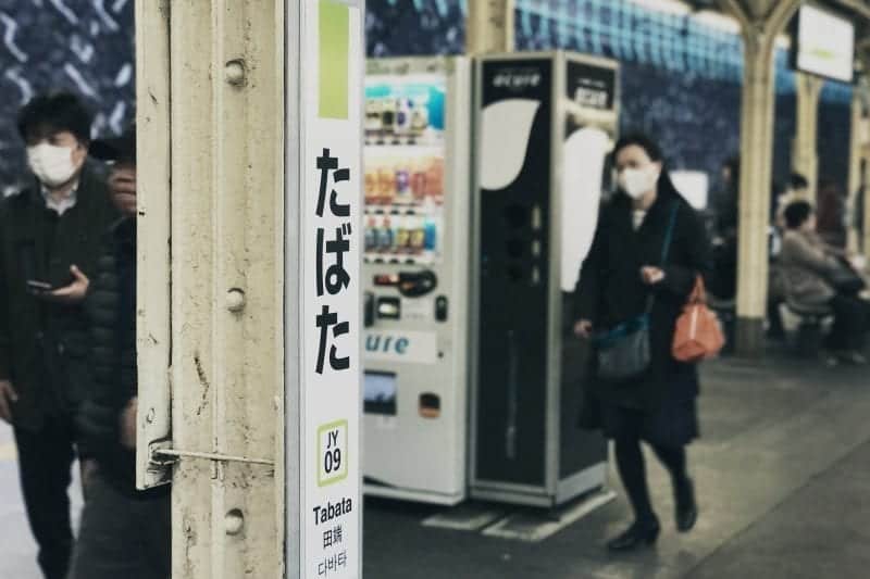 Cosas extrañas sobre Japón, peatones en la plataforma de la estación de tren con máscaras faciales blancas