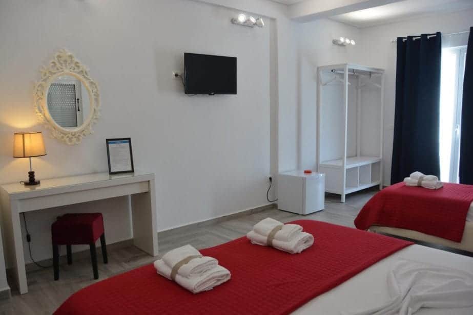 Explore los hoteles de Saranda en la playa, la habitación del hotel con sábanas blancas y rojas completas con ordenadas pilas de toallas y un escritorio junto a la pared