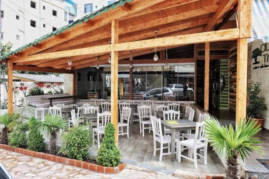 Hospédese en el mejor hotel de Albania, con asientos al aire libre cubiertos con sillas de madera blanca y mesas grises