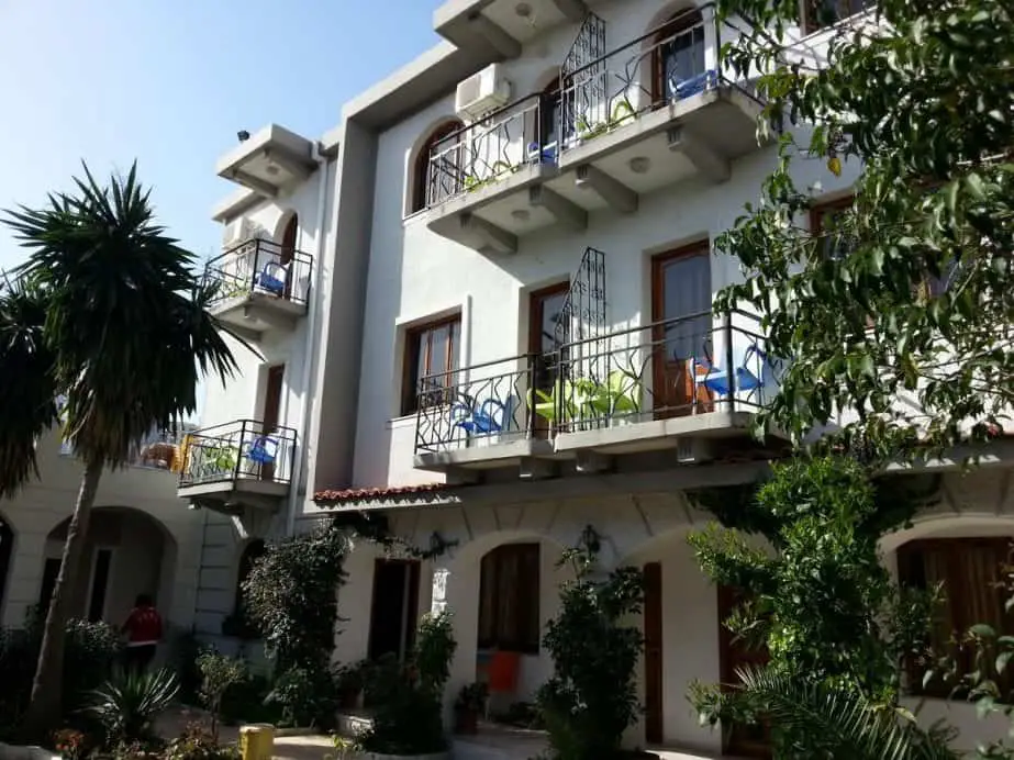 Increíbles hoteles en Saranda, Albania, edificio blanco de dos plantas con balcones de estructura metálica y plantas verdes repartidas por la entrada principal