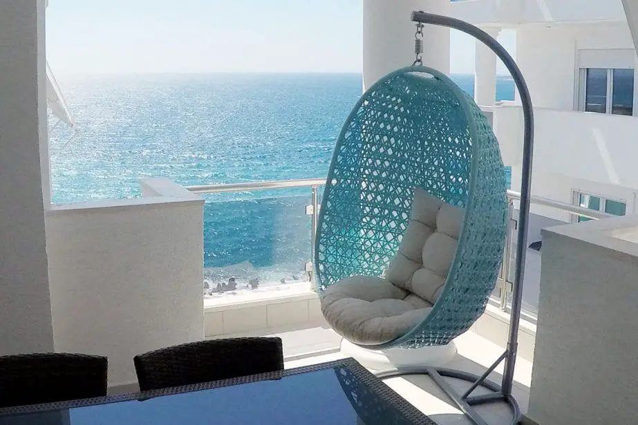 Encuentre los mejores hoteles en Saranda, esquina de la habitación que contiene una silla de huevo colgante con cojines con vista al mar desde la ventana