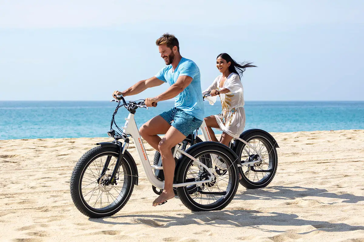 Pareja feliz en un tour en bicicleta por la playa 