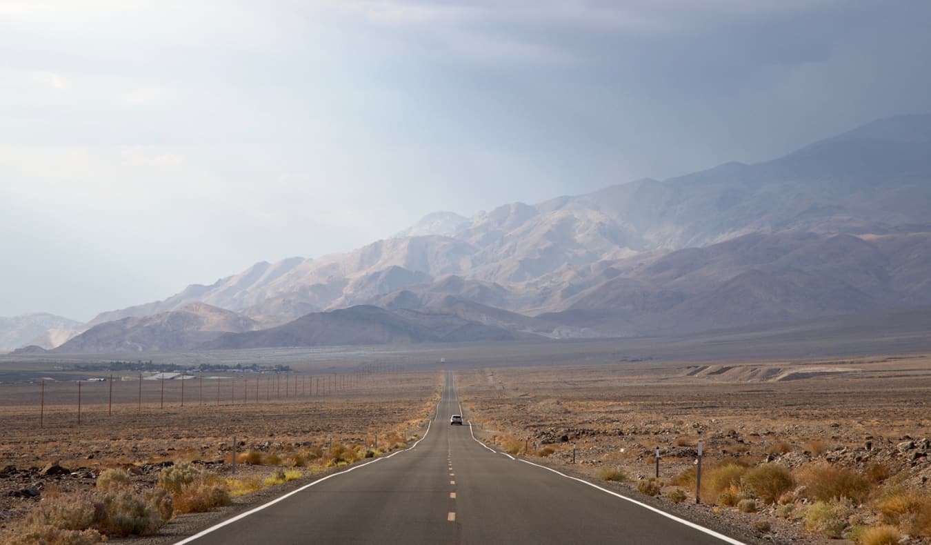 Un automóvil que conduce un camino abierto en Death Valley, los E.E.U.U.
