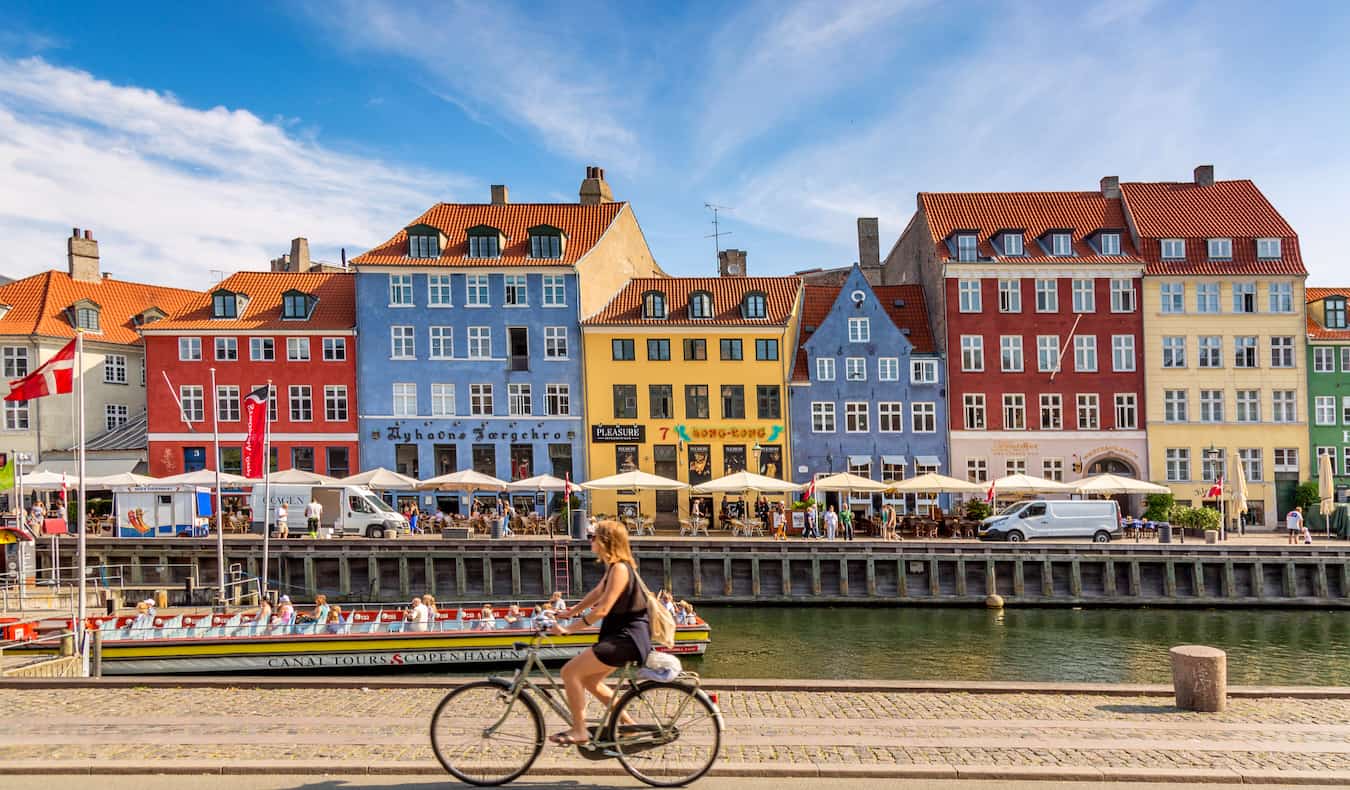 Los coloridos edificios de Copenhague a lo largo del agua mientras alguien pasa en bicicleta