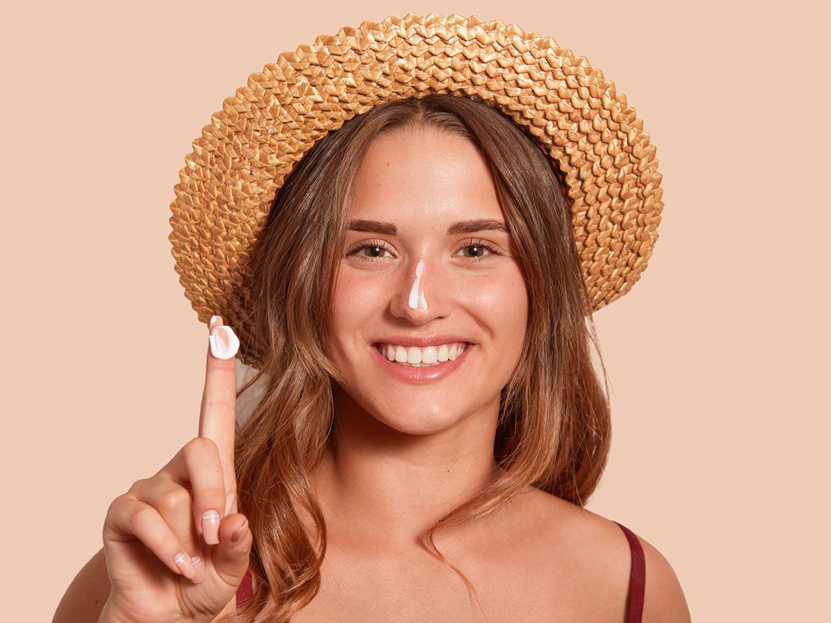 Mujer sonriendo con protector solar en el dedo 
