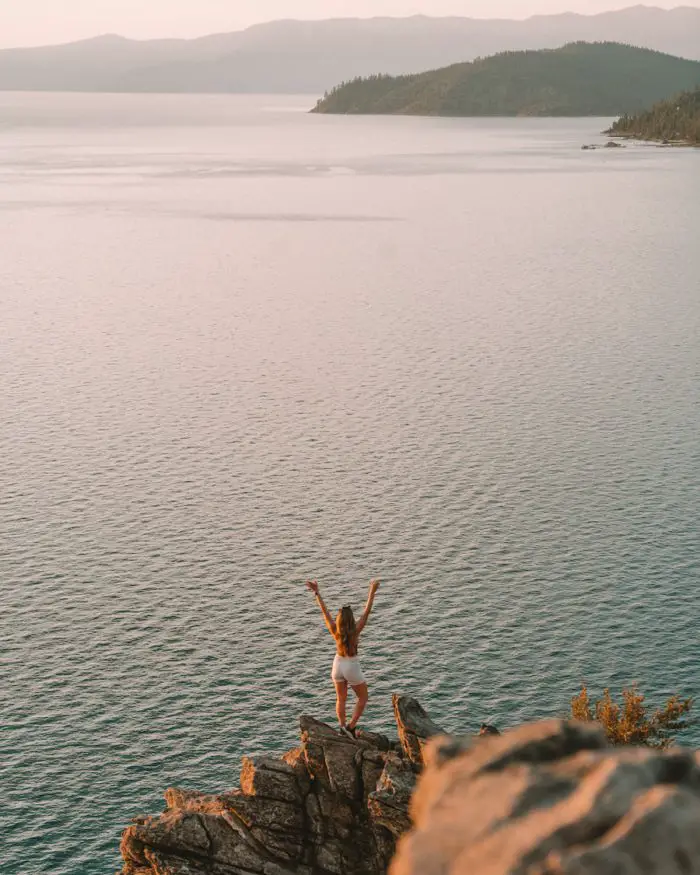 Michelle Halpern posando en una roca con vista al lago Tahoe - vista desde Cave Rock