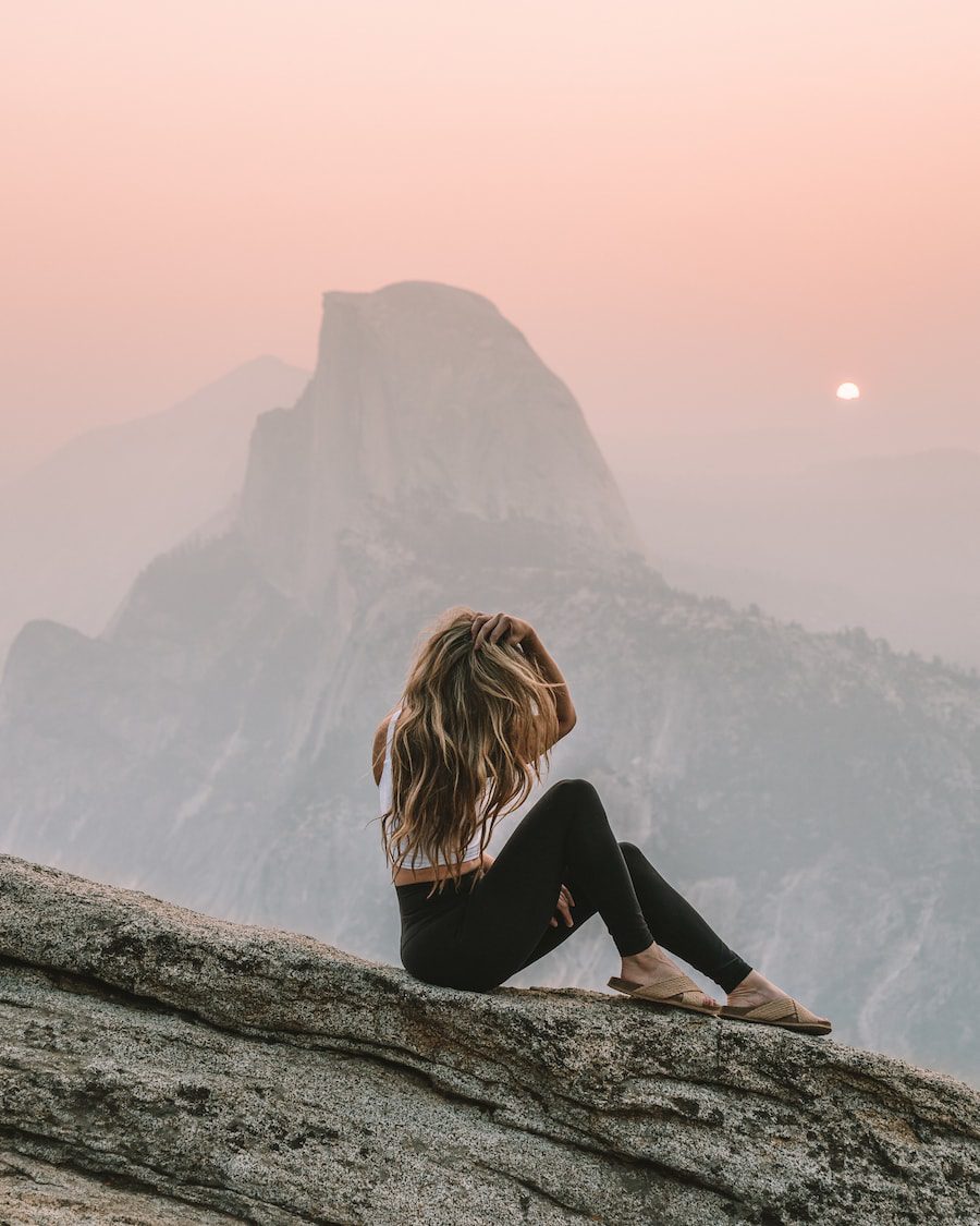 Chica sentada frente a Half Dome en Glacier Point al amanecer para saber dónde visitar en Calfornia en primavera