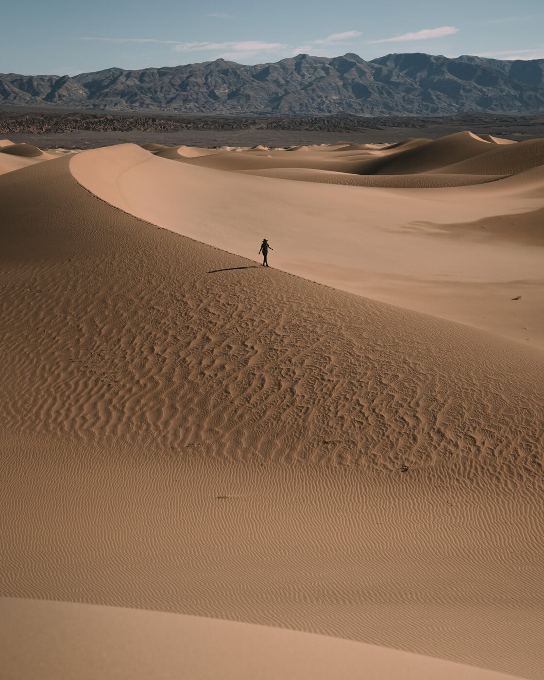 Pequeña persona caminando por las dunas de arena en Death Valley